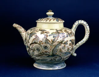 Staffordshire Creamware teapot known as The Tunstall Teapot decorated with three birds in oriental foliage, painted in brownish manganese the outline heightened in blue and green underglaze by F. Morg